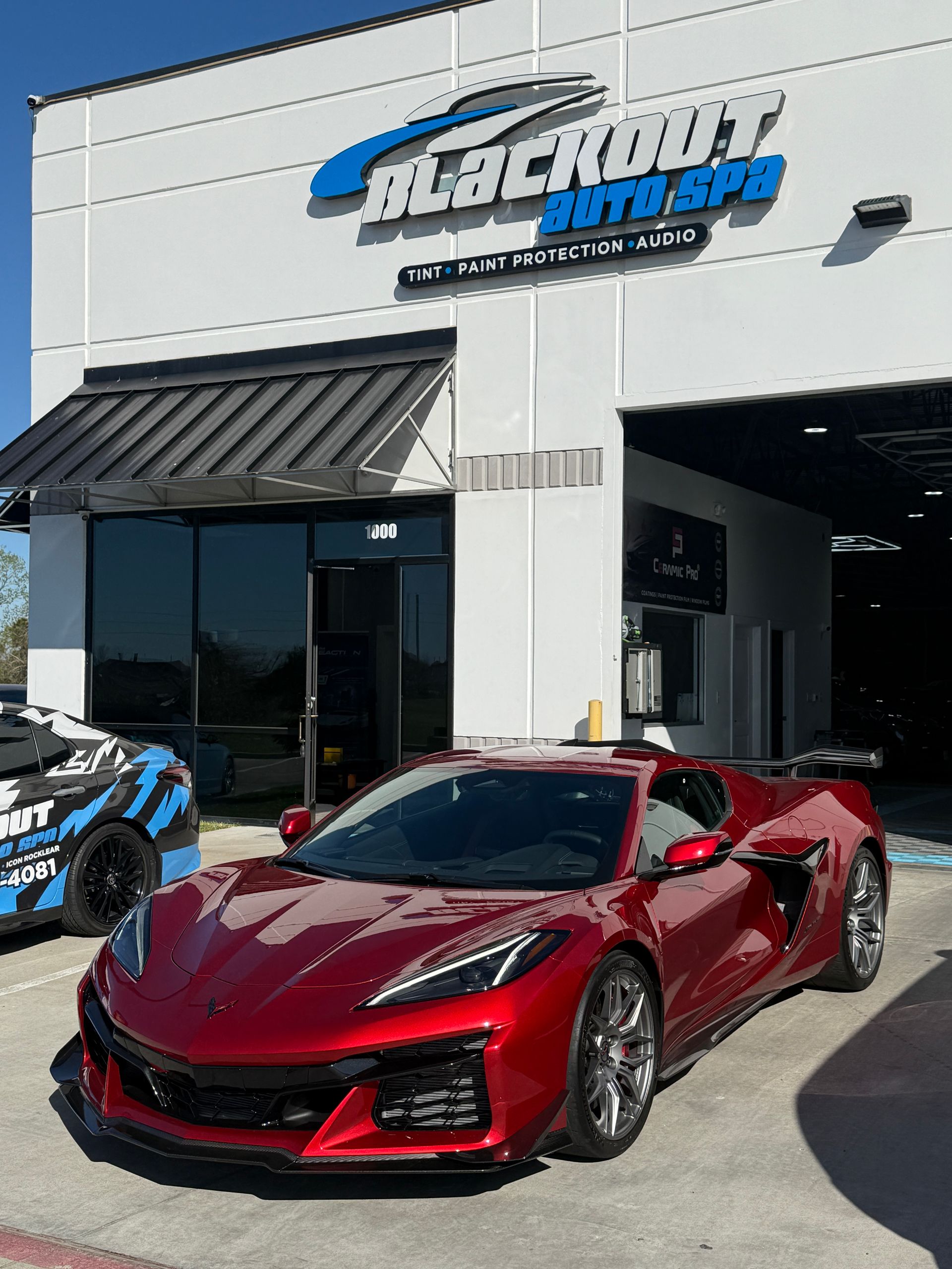 Red sports car parked in front of Blackout Auto Spa, a car detailing business.
