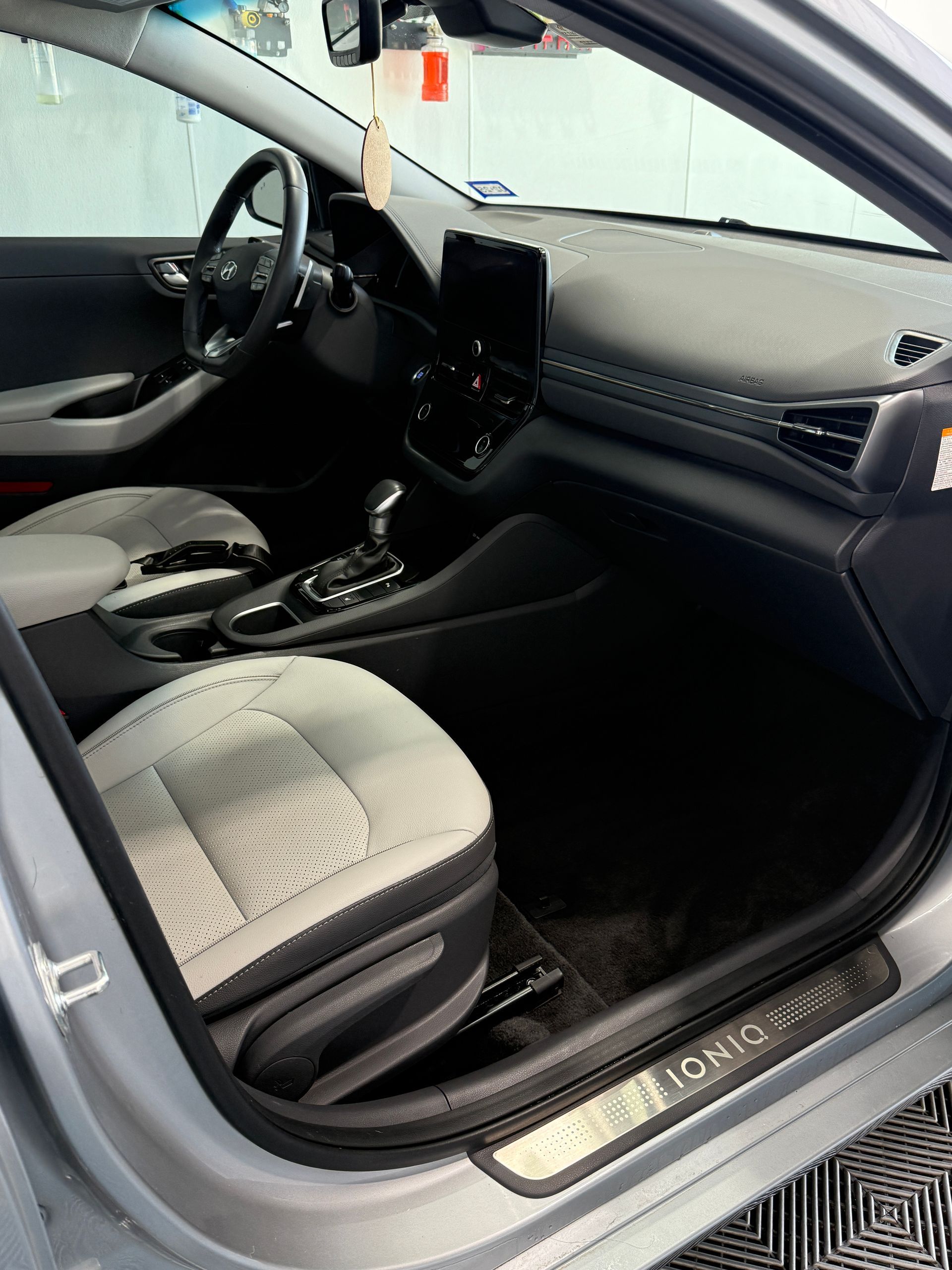 Interior of a silver Hyundai Ioniq hybrid car with gray and white seats, dashboard, and black console.