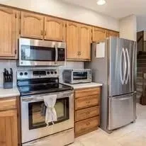 A kitchen with a stove, refrigerator, microwave, and toaster oven.