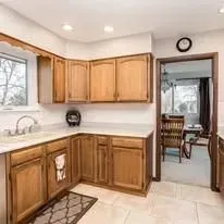 A kitchen with wooden cabinets, a sink, and a clock on the wall.