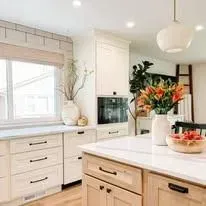 A kitchen with white cabinets and a large island with flowers on it.