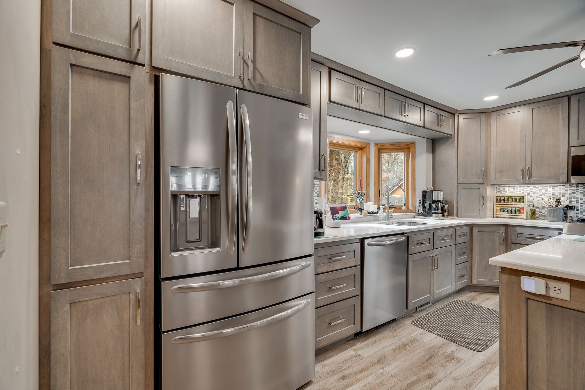 Modern kitchen with light gray cabinets, stainless steel appliances, and a window.