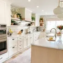 A kitchen with white cabinets, stainless steel appliances, a sink, and a large island.