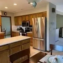 A kitchen with a stainless steel refrigerator and a dining table.