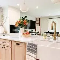 A kitchen with a sink, cabinets, and a vase of flowers on the counter.