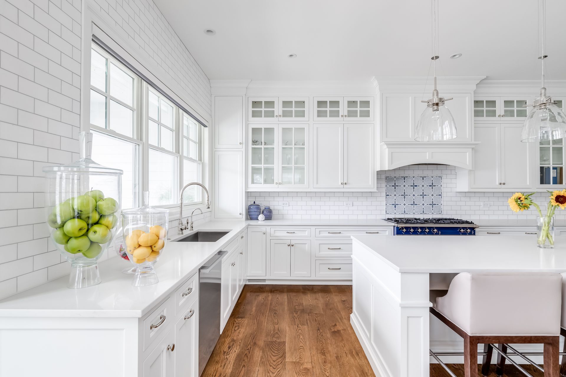 White kitchen with hardwood floors, a large island, and subway tile backsplash.