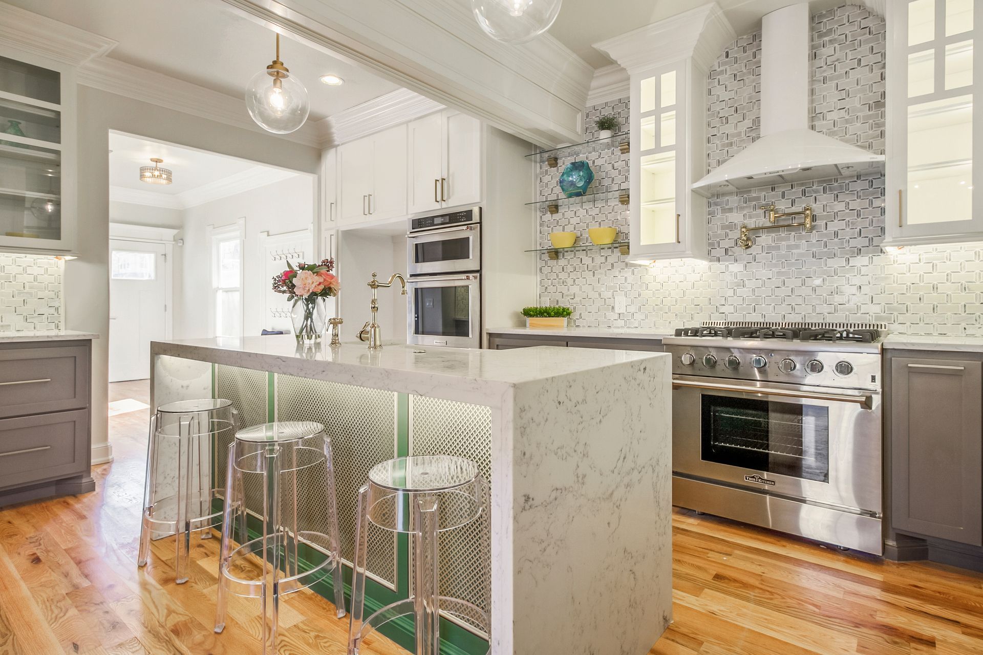 Modern kitchen with island, stainless steel appliances, white cabinetry, and hardwood floors.