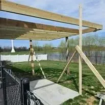 A wooden pergola is being built in a backyard.