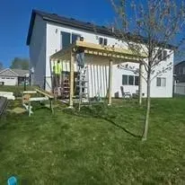 A white house with a wooden deck under construction in the backyard.