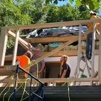 A group of people are working on a wooden structure.