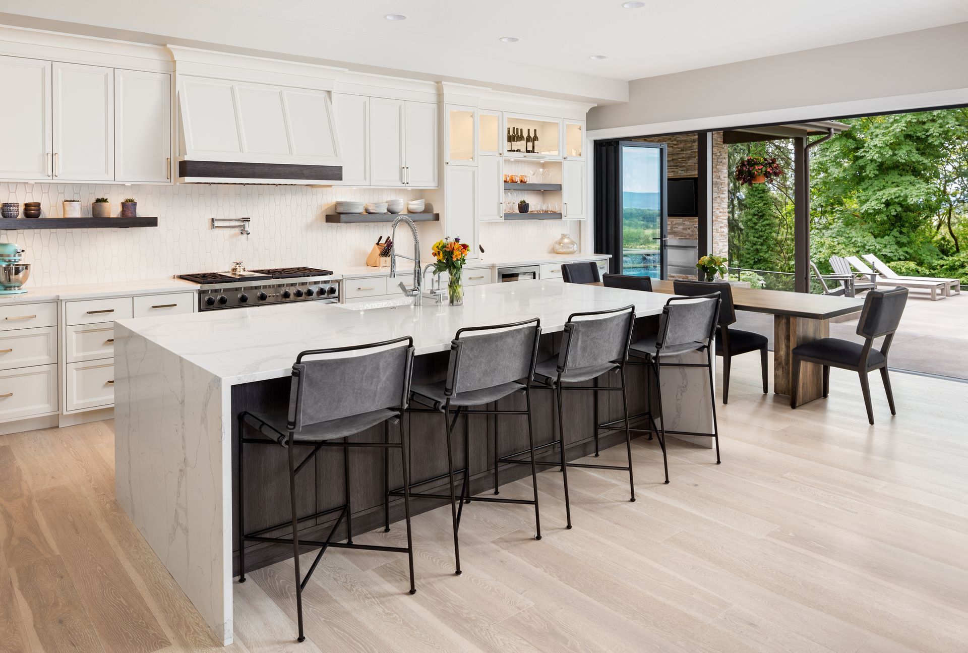 Modern kitchen with white cabinets, large island with seating, and open to a deck.