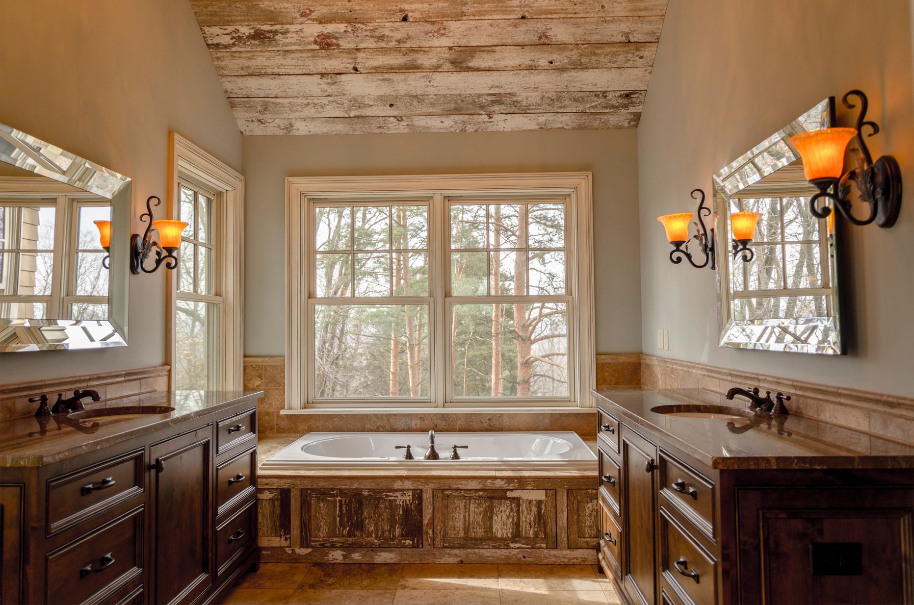 Bathroom with dark wood vanities, large window overlooking trees, and ornate light fixtures.