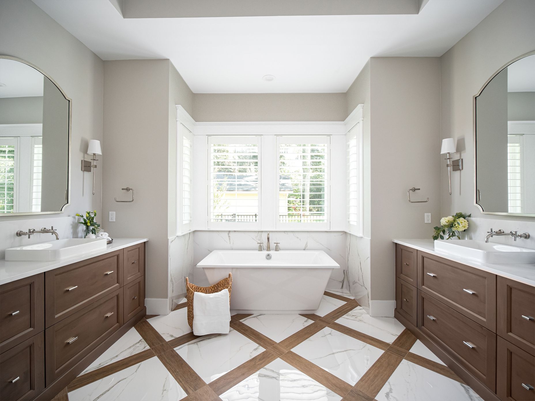 Elegant bathroom with a free-standing tub, dual vanities, and diamond-patterned marble and wood floor.
