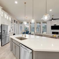 A kitchen with a large island , sink , refrigerator and dishwasher.