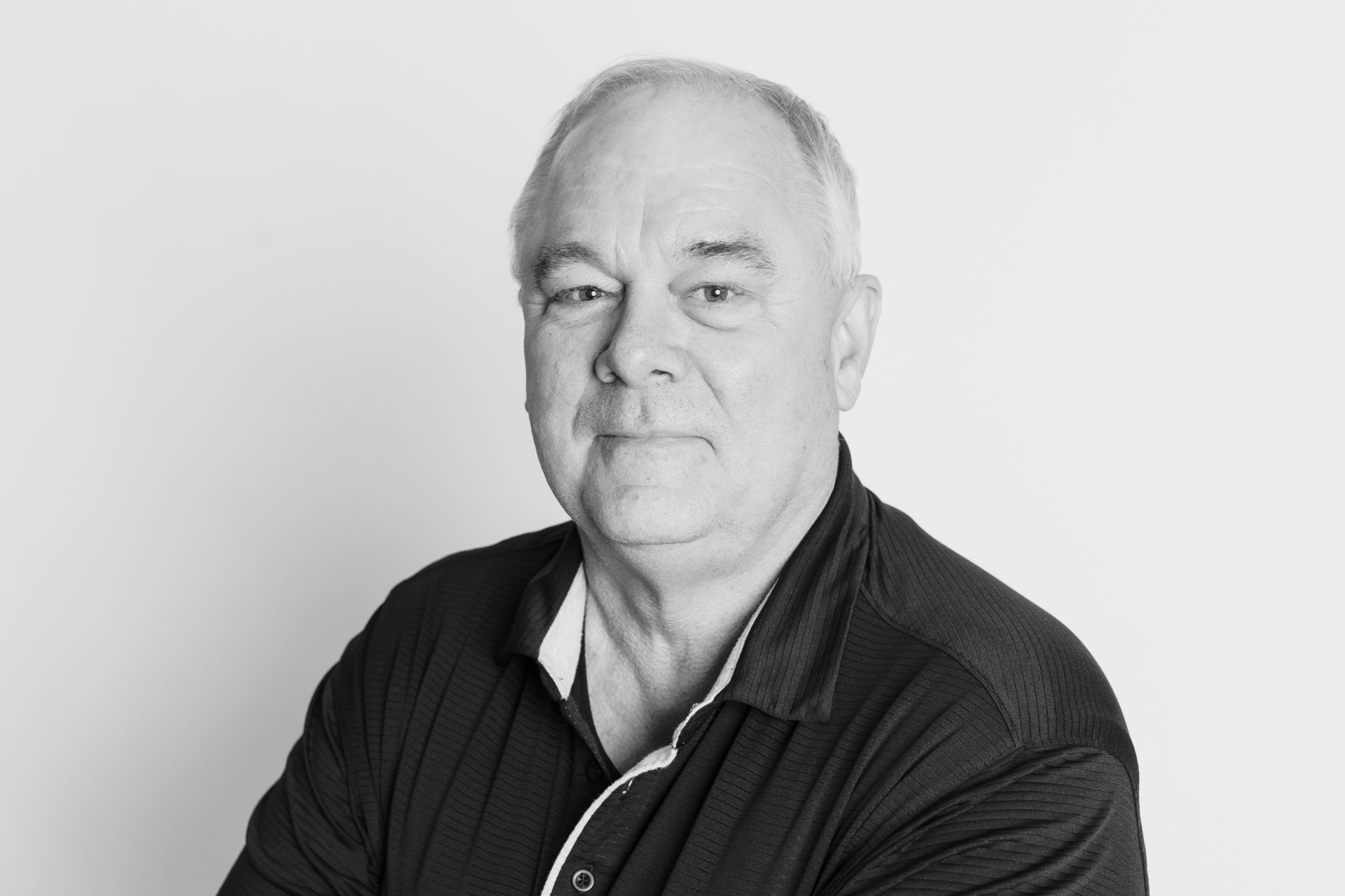 Black and white headshot of a person looking directly at the camera with a neutral expression against a plain background.