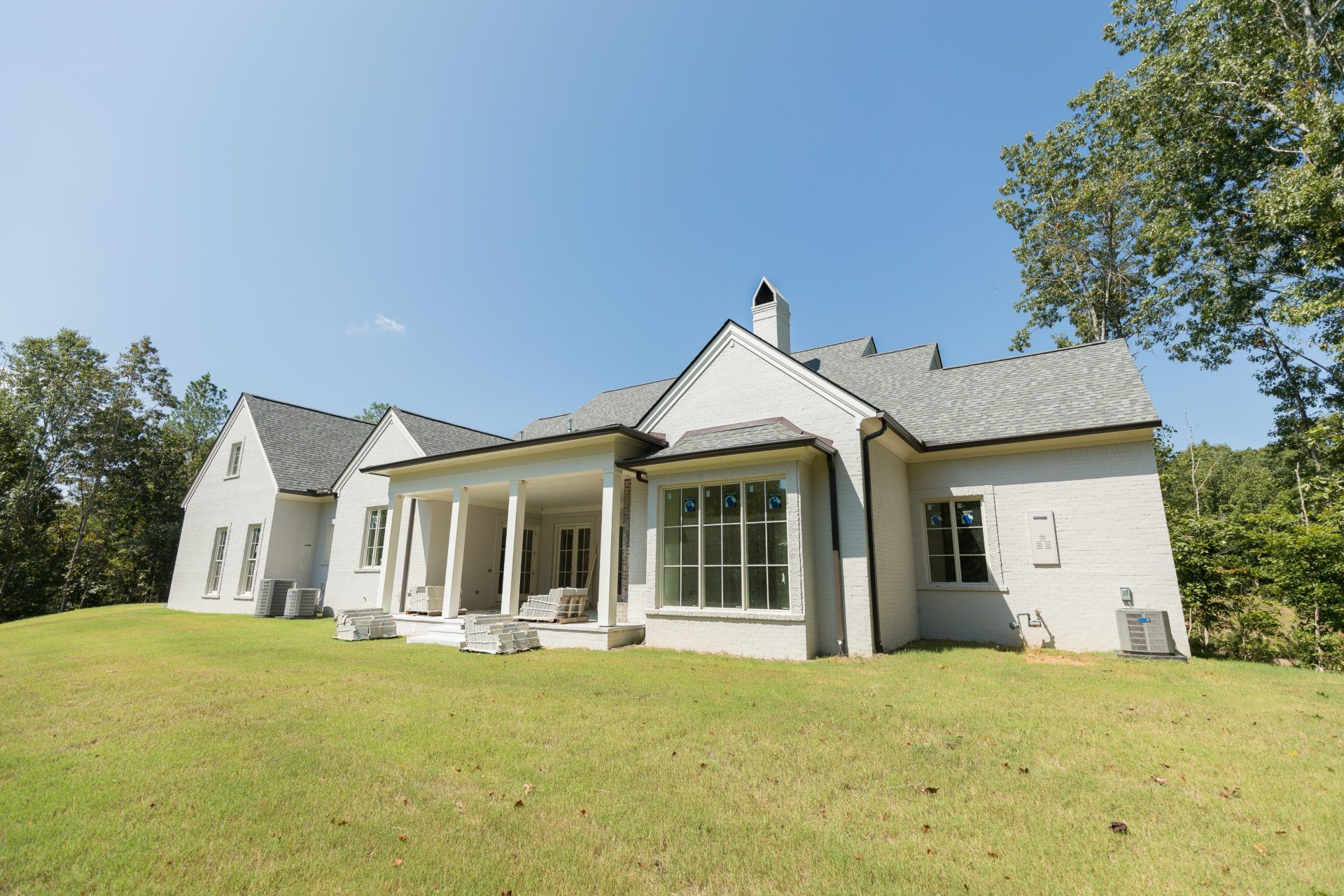 White country house with a porch and large windows on a sunny lawn