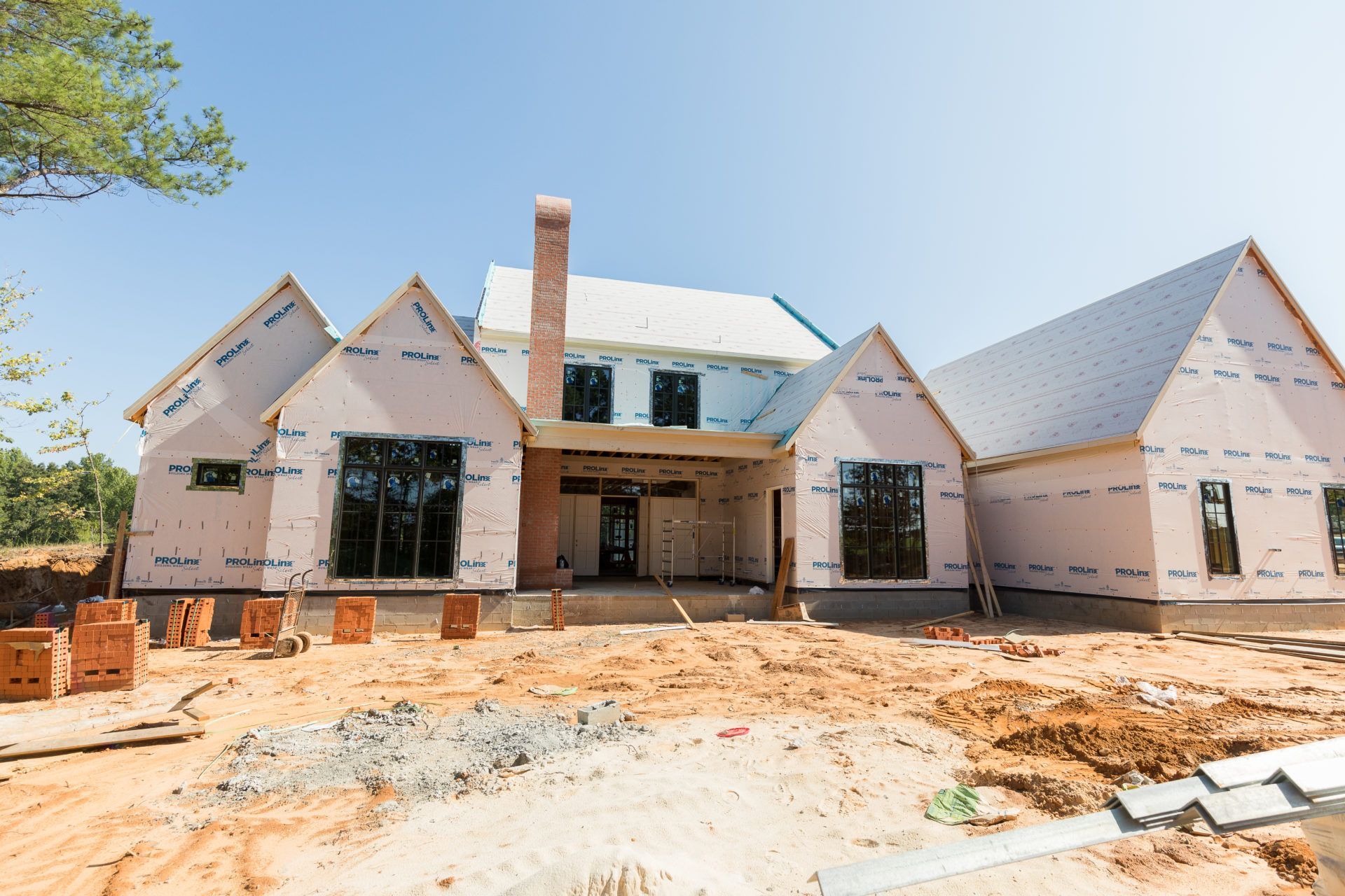 New house under construction with white exterior walls and exposed dirt in front