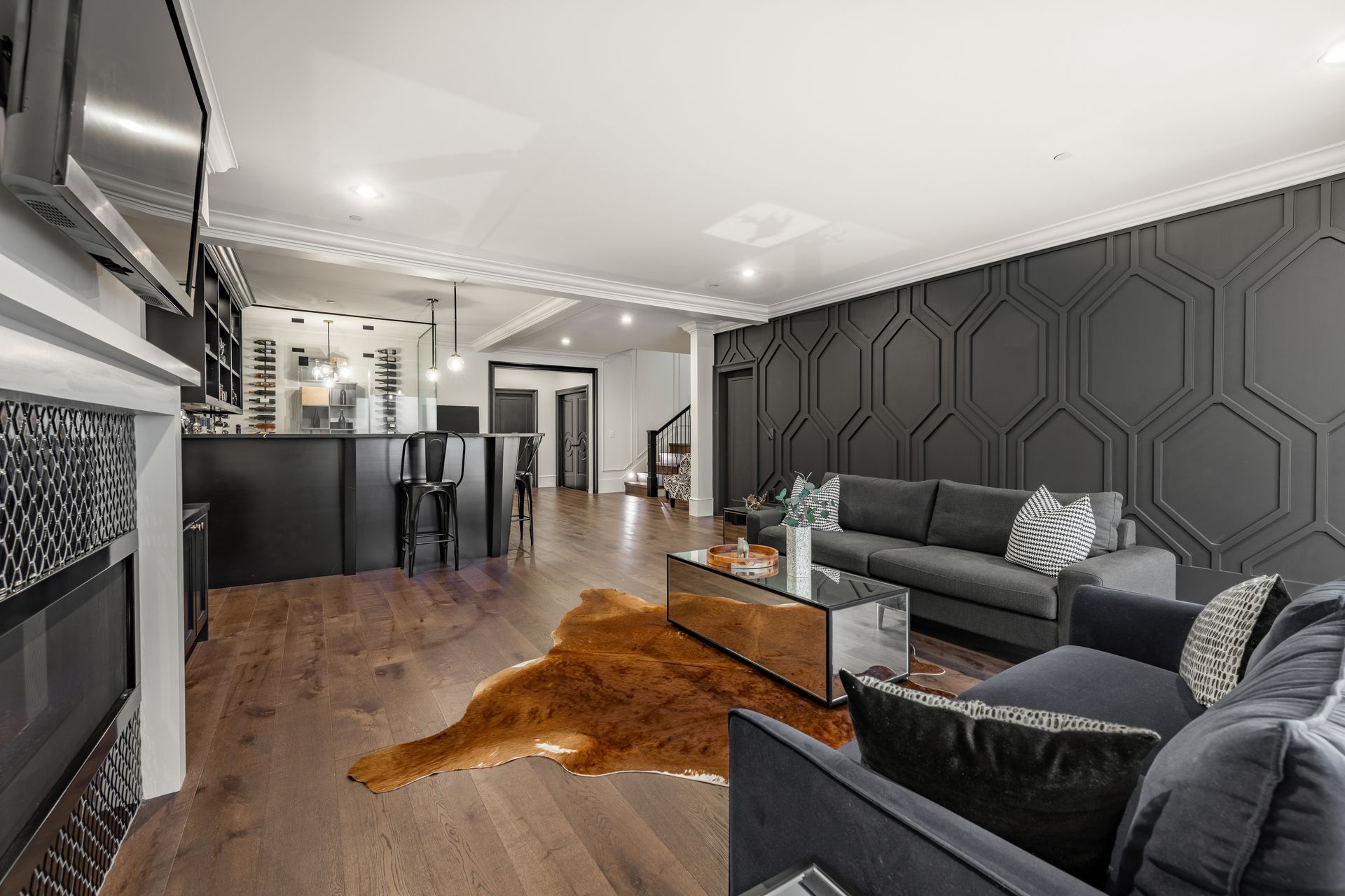 Living room with dark gray geometric accent wall, gray sofa, fireplace, and bar.