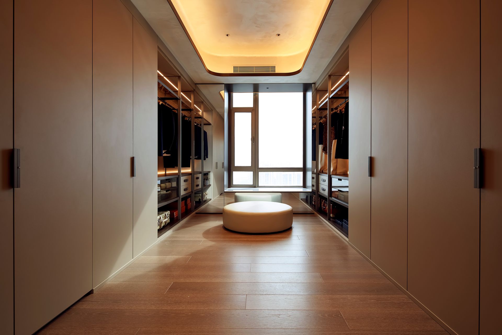 Walk-in closet with beige cabinets, window seat, and wood floors. Recessed lighting.