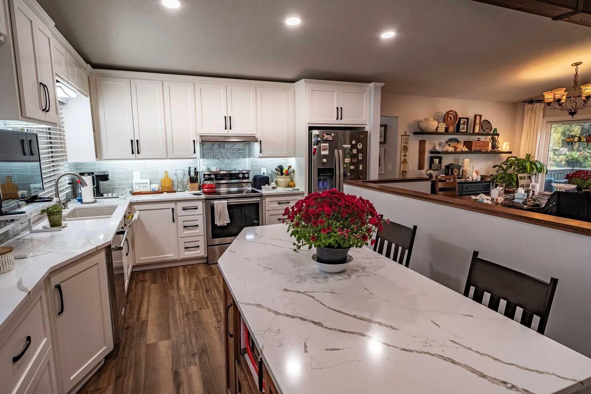 Kitchen with white cabinets, quartz countertops, and a dining table with a floral centerpiece.