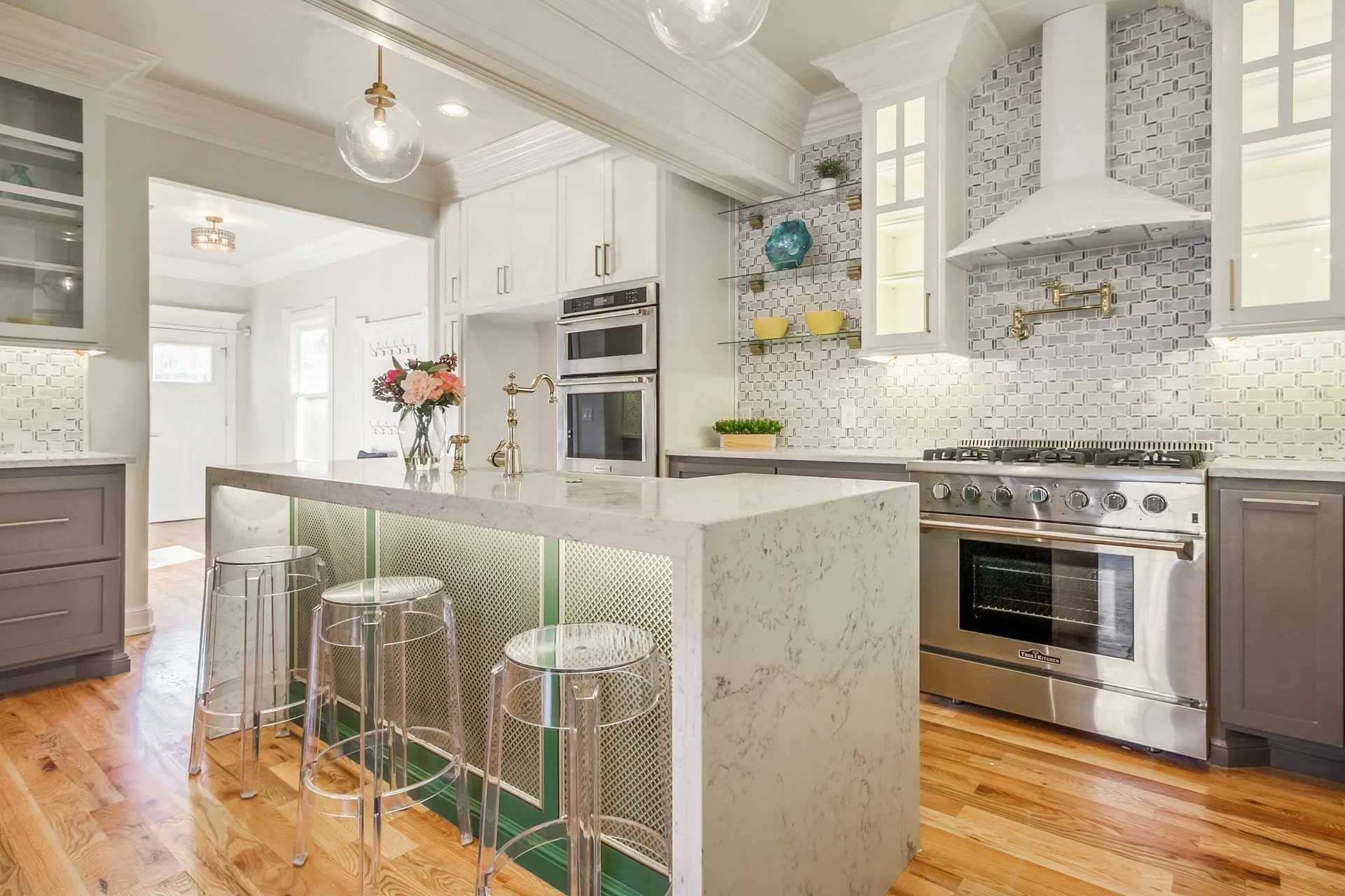 Modern kitchen with white cabinets, island, stainless steel appliances, and wooden floor.