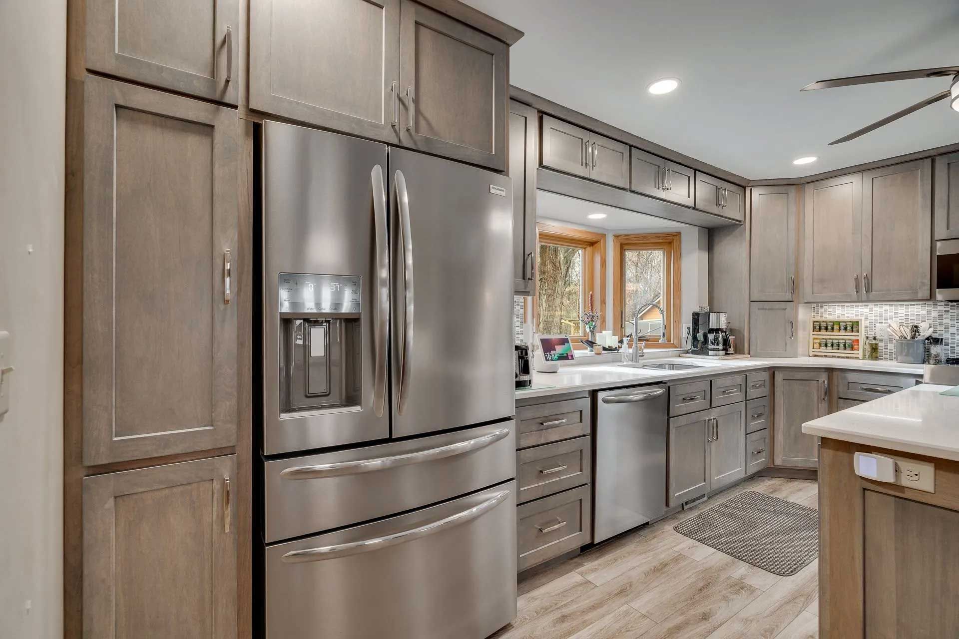 Kitchen with gray cabinets, stainless steel appliances, and a window over the sink.