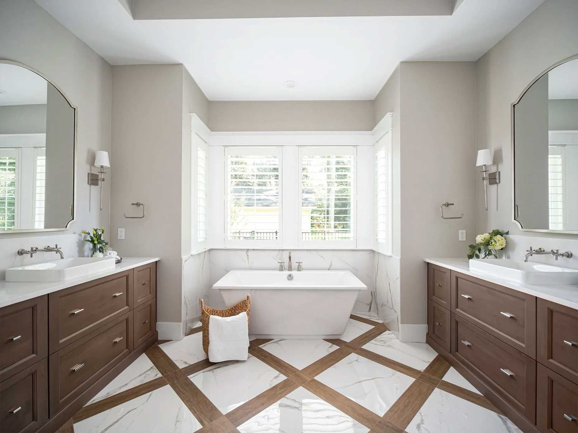 Bathroom with dual vanities, freestanding tub, and a window. Light wood and marble floor.