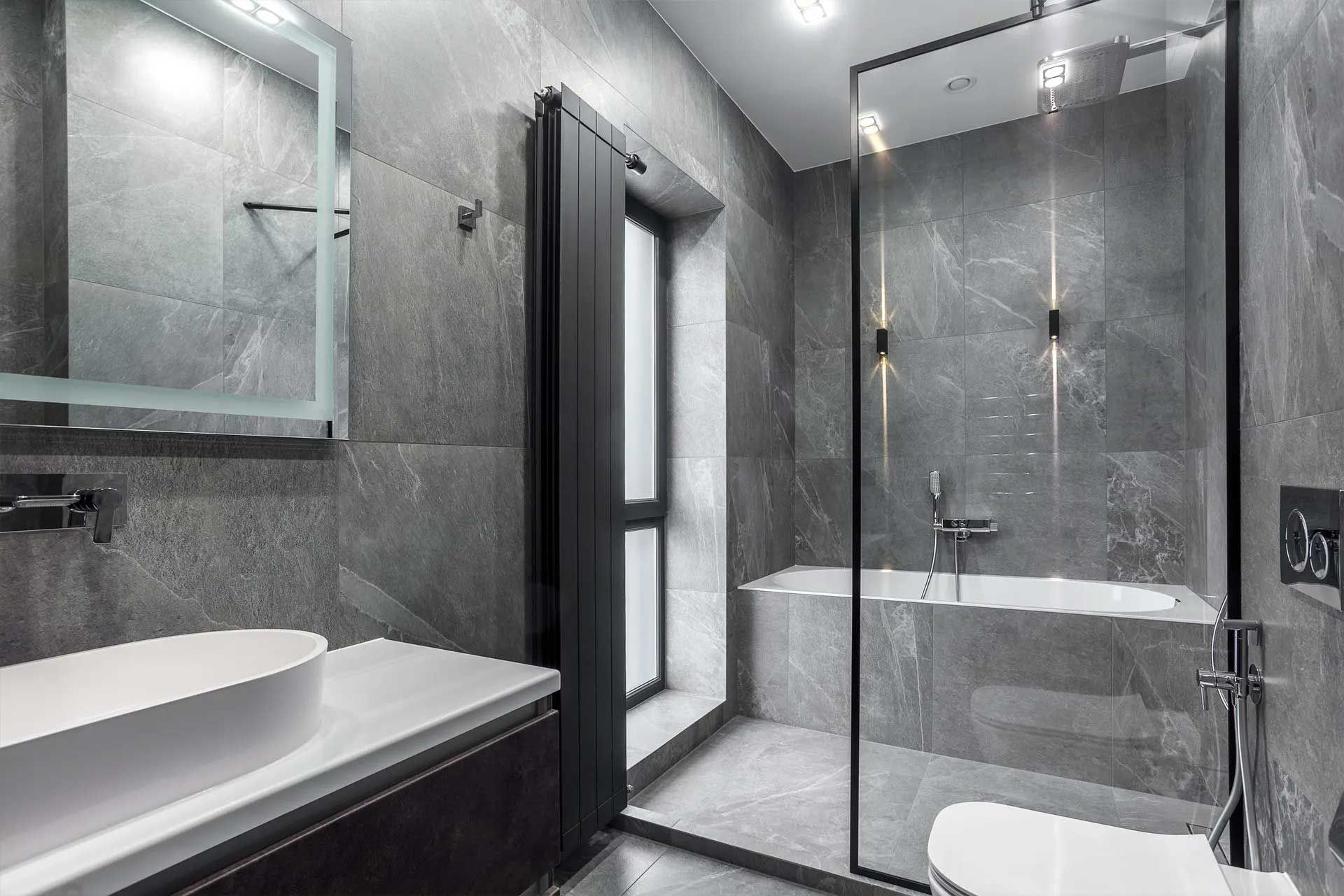 Gray tiled modern bathroom with a shower, bathtub, toilet, and sink.
