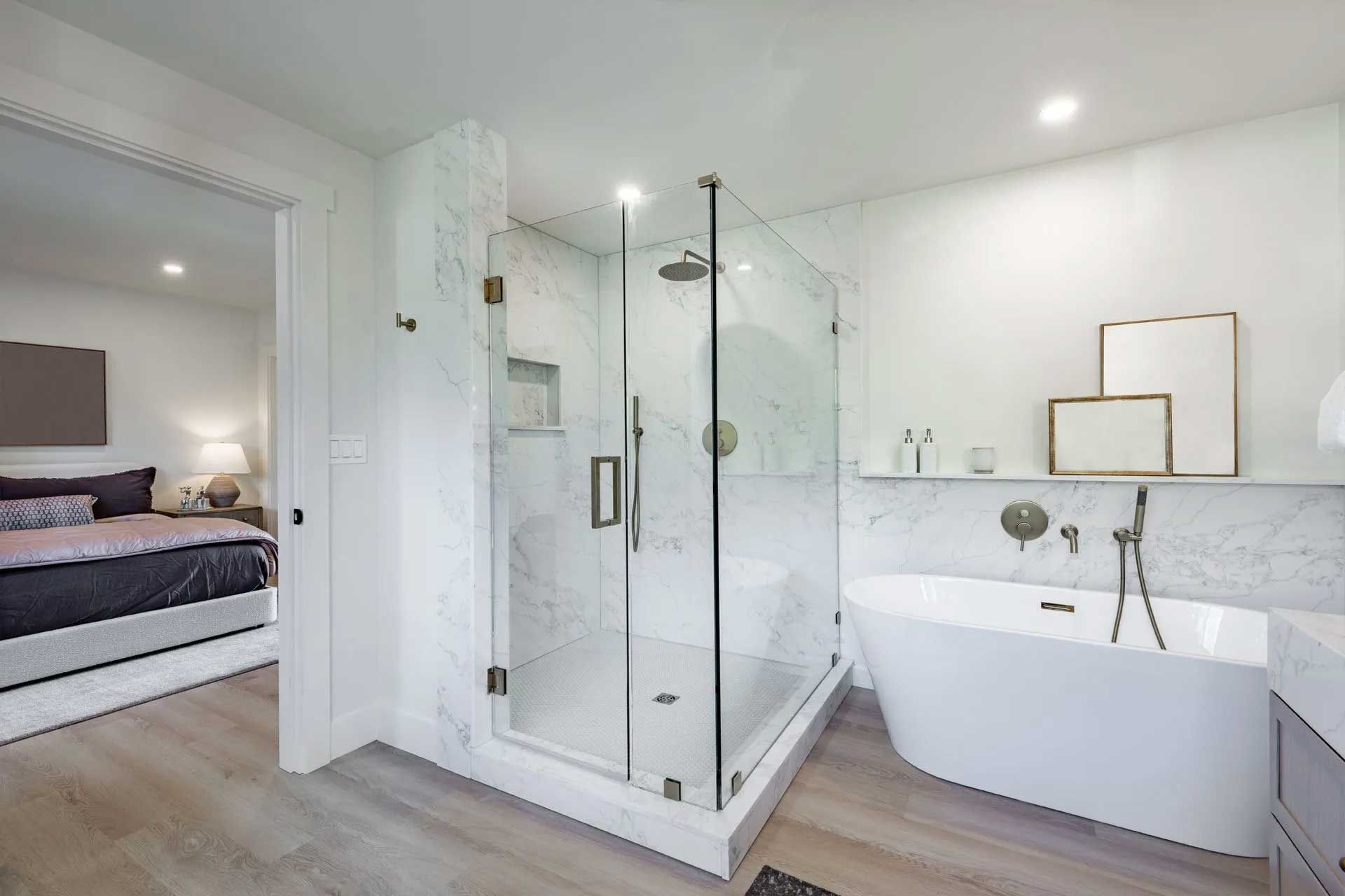 Modern bathroom with glass shower, freestanding tub, and open doorway to a bedroom.