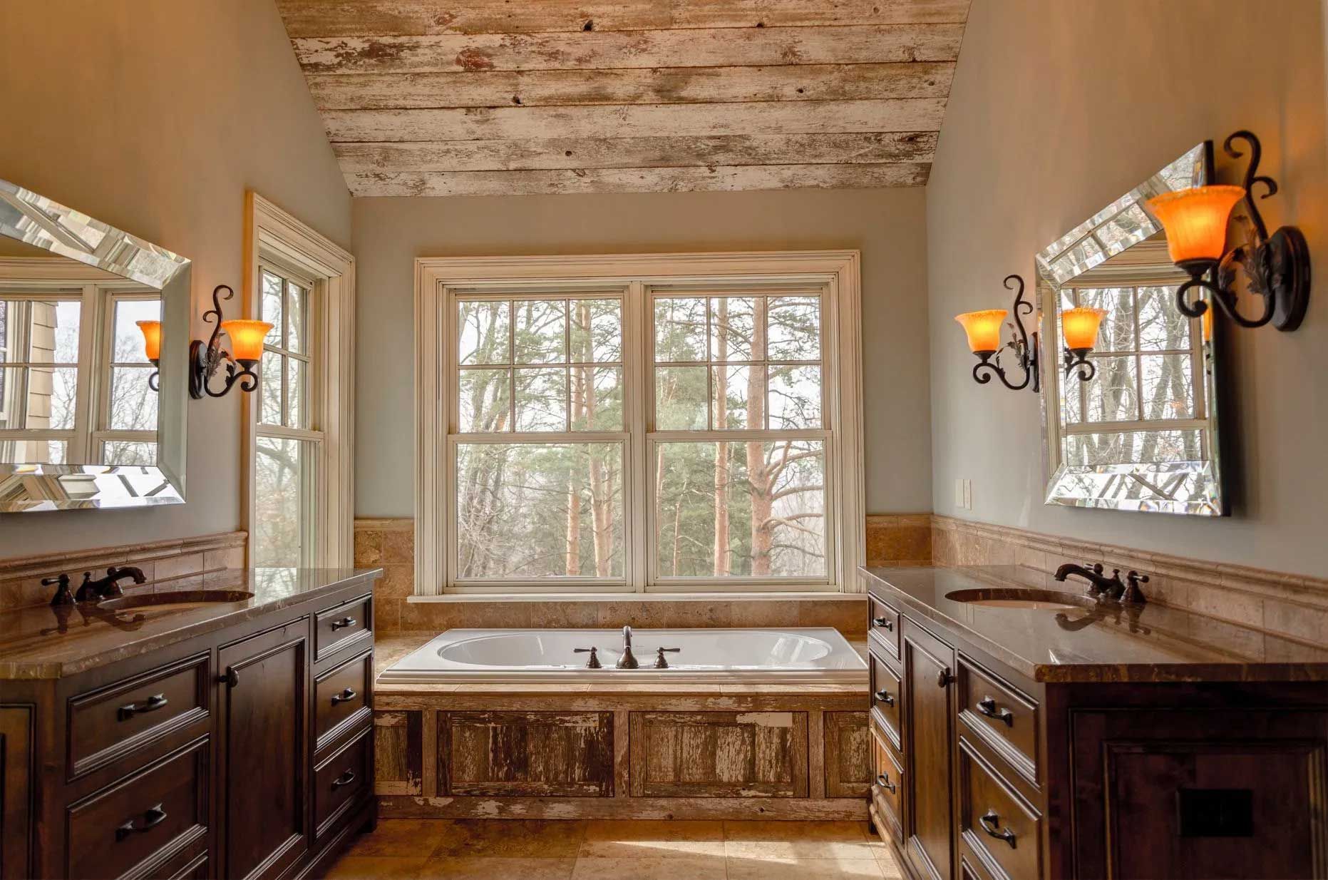Bathroom with wood accents, two vanities, a tub, and a large window overlooking trees.