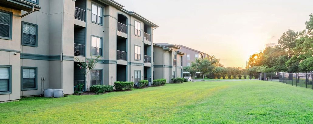 Apartment complex with green lawn at sunset.