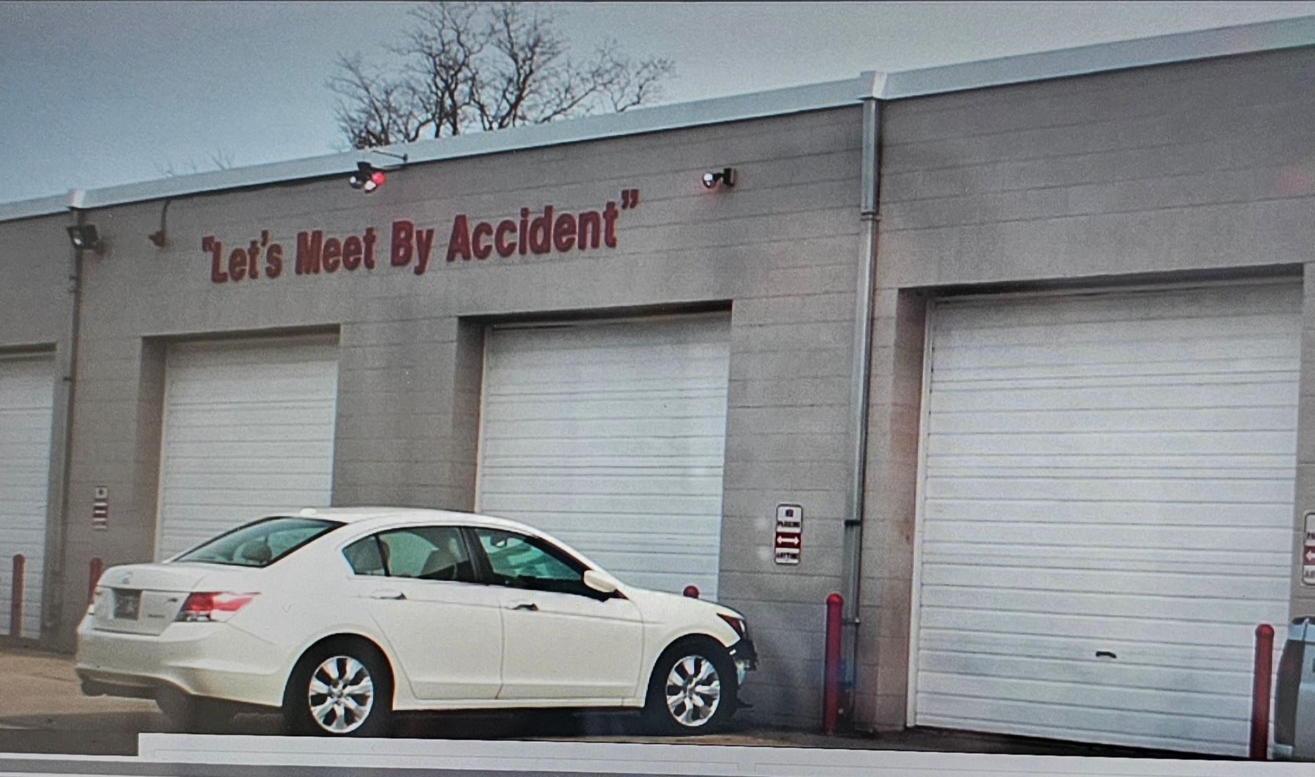 A white car is parked in front of a building that says let's meet by accident