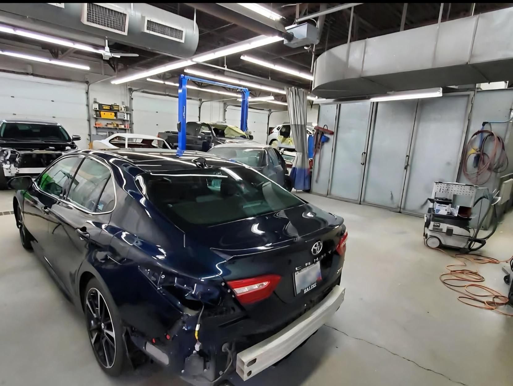 A blue car is parked in a garage with other cars.