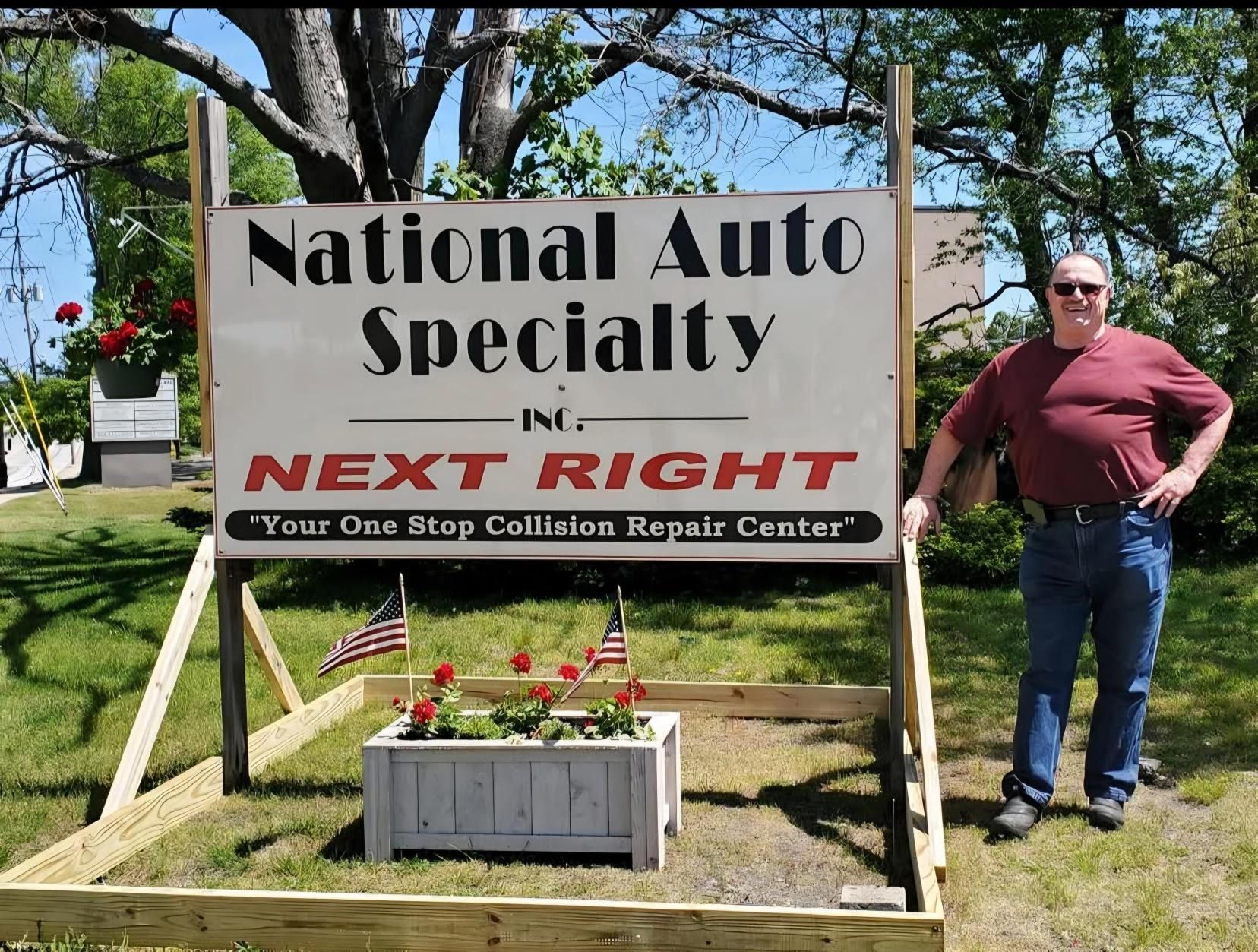 A man stands in front of a national auto specialty sign