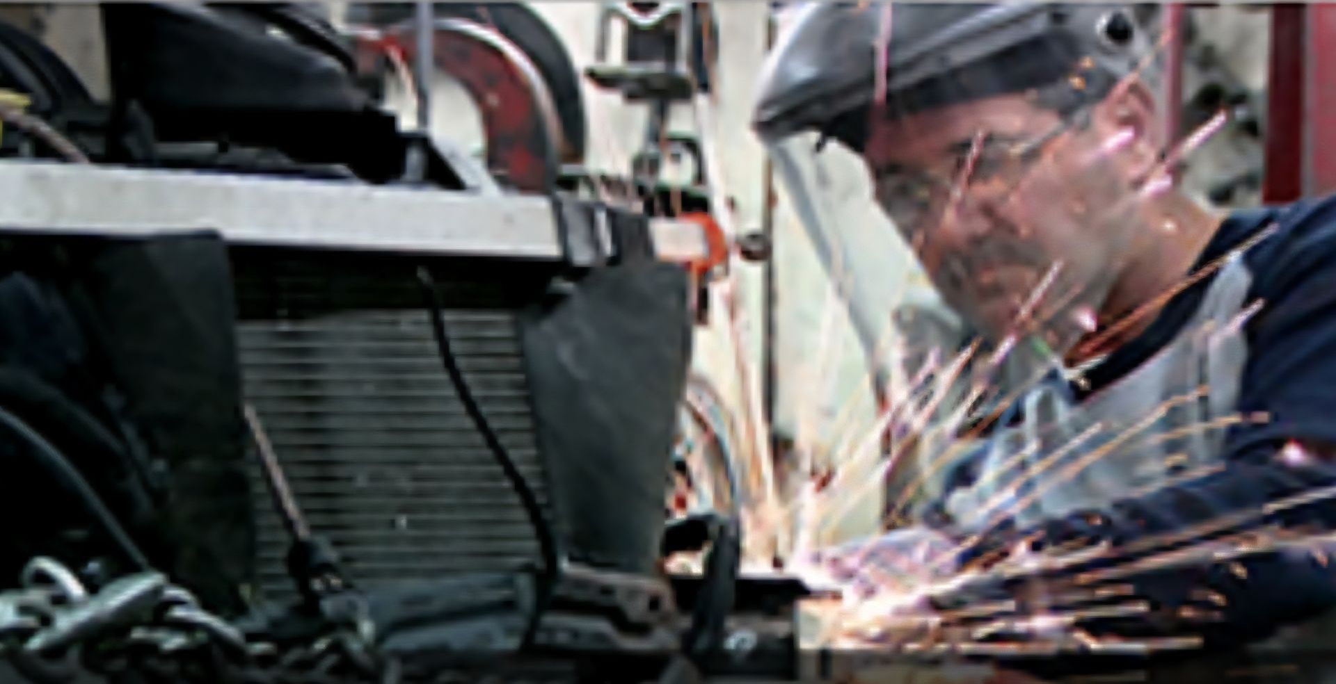 A man wearing a welding helmet is welding a piece of metal.