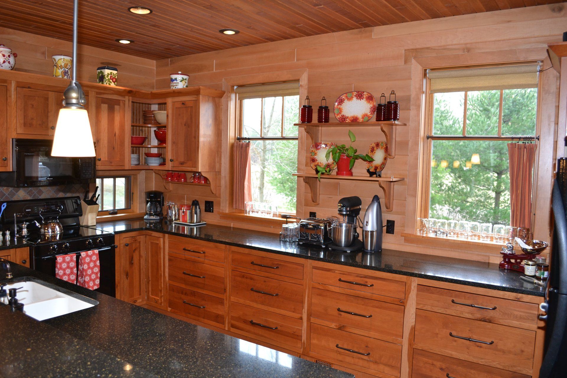 A kitchen with wooden cabinets and black counter tops