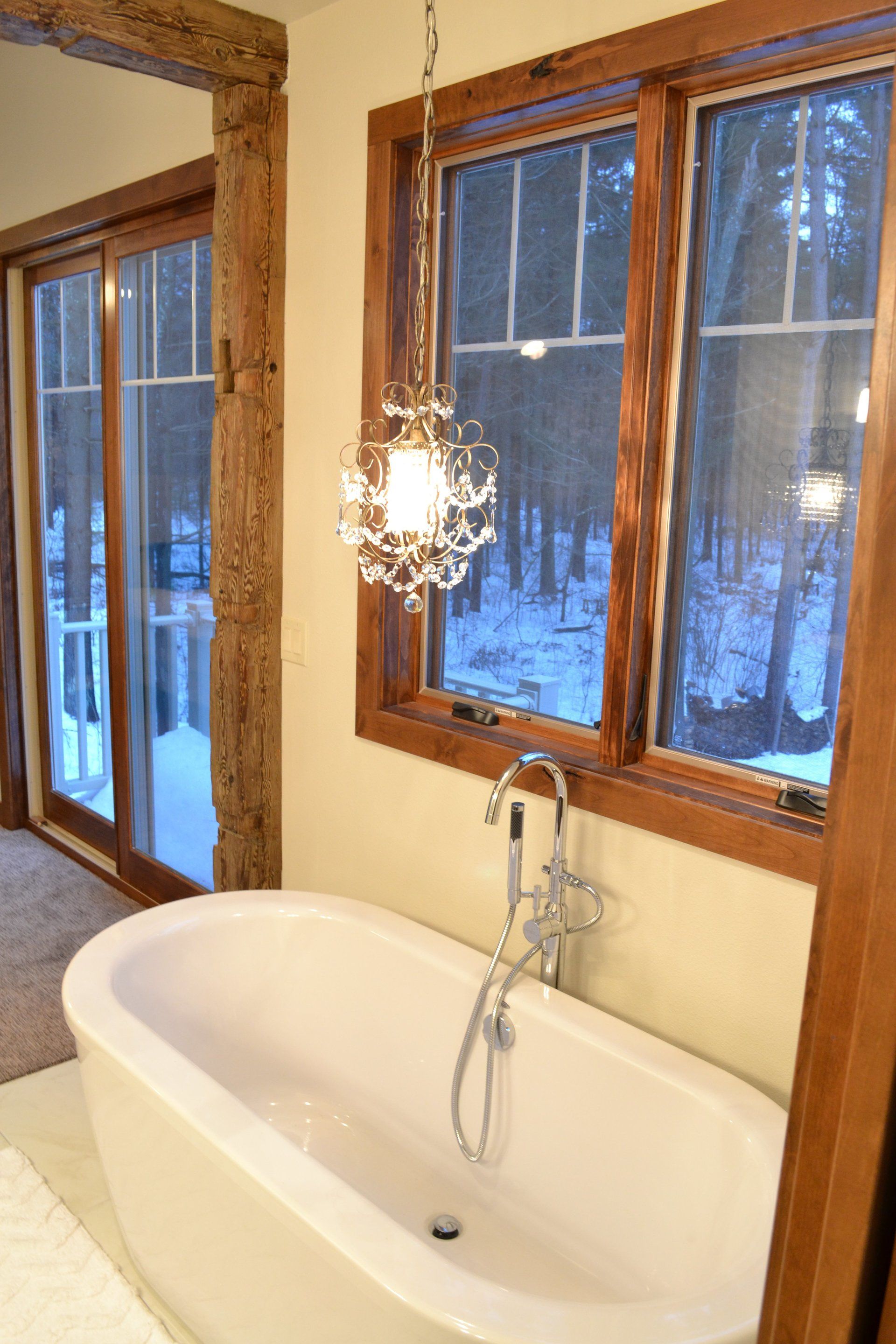 A bathtub in a bathroom next to a window with a light hanging from it.
