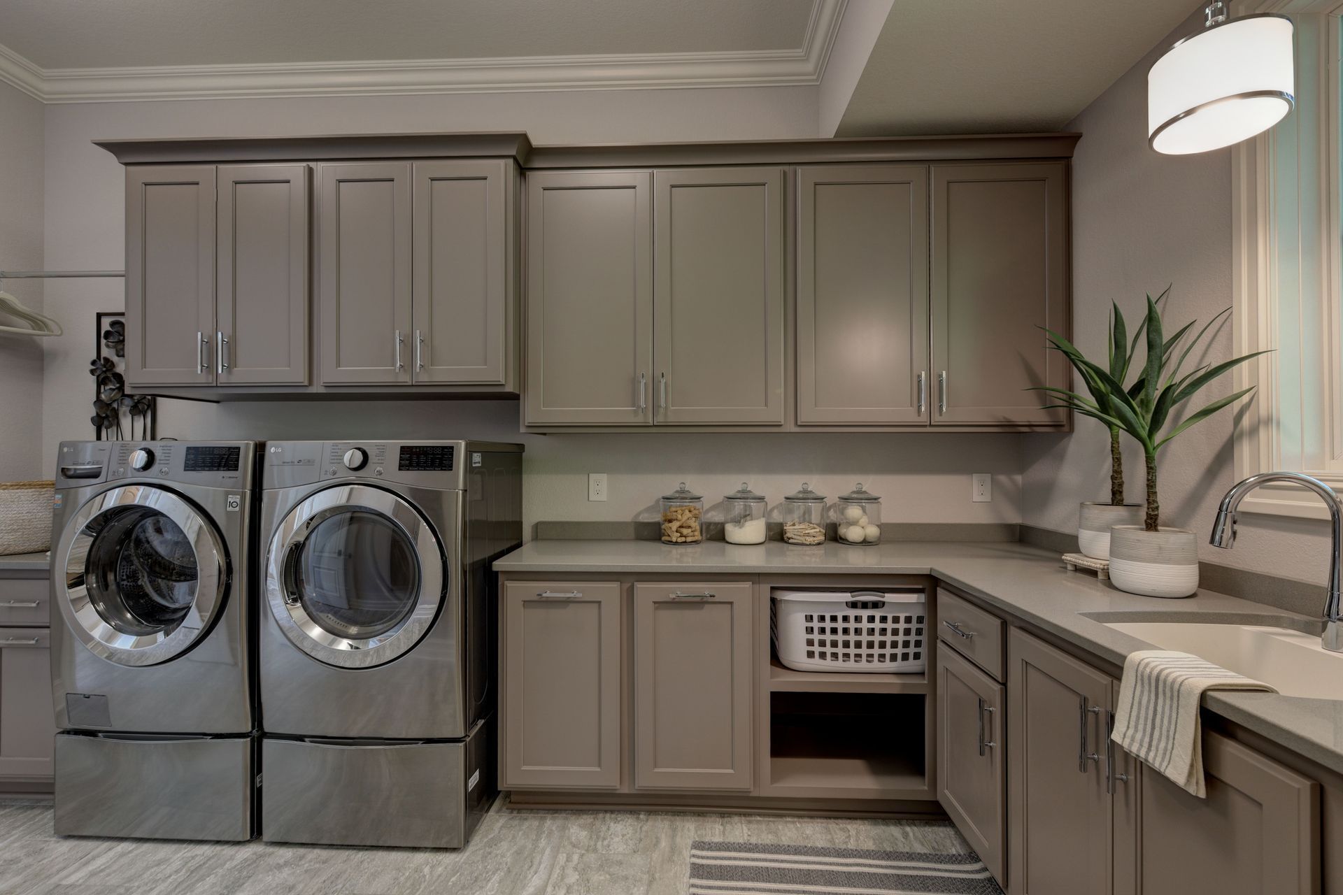 Laundry room with gray cabinets, washer/dryer, sink, and decorative items.