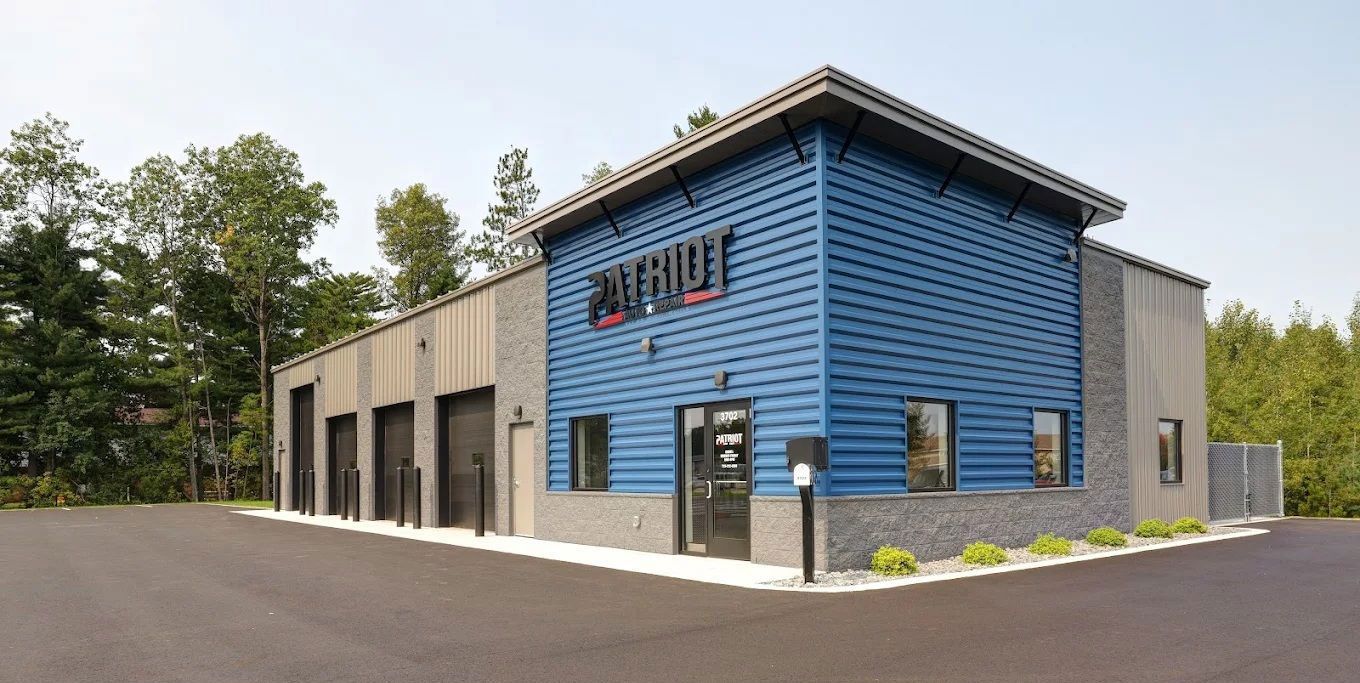 Blue and gray industrial building with black garage doors and paved driveway.