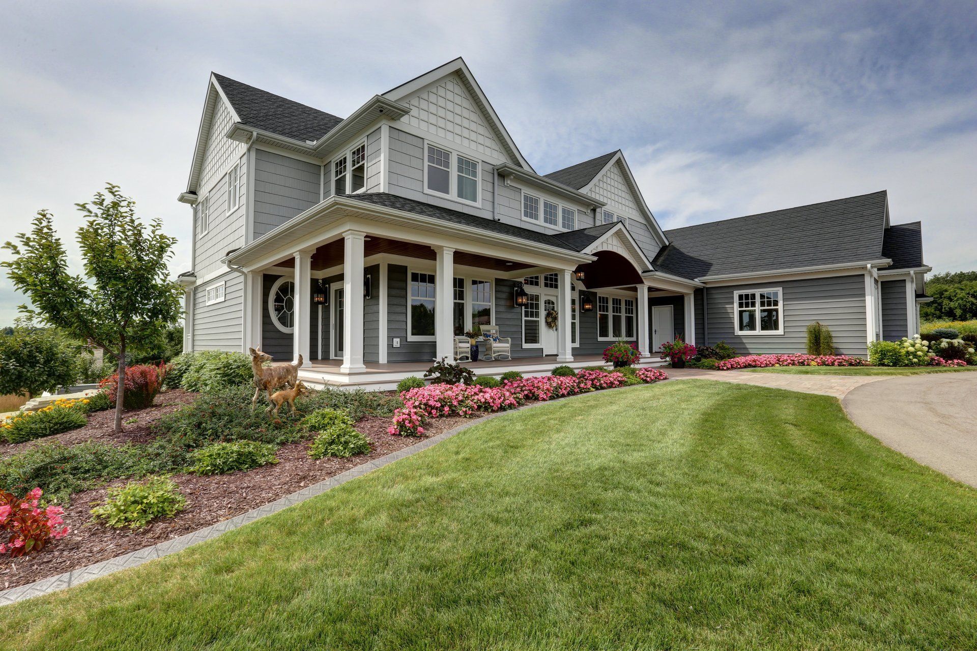 A large house with a large porch and a lush green lawn.
