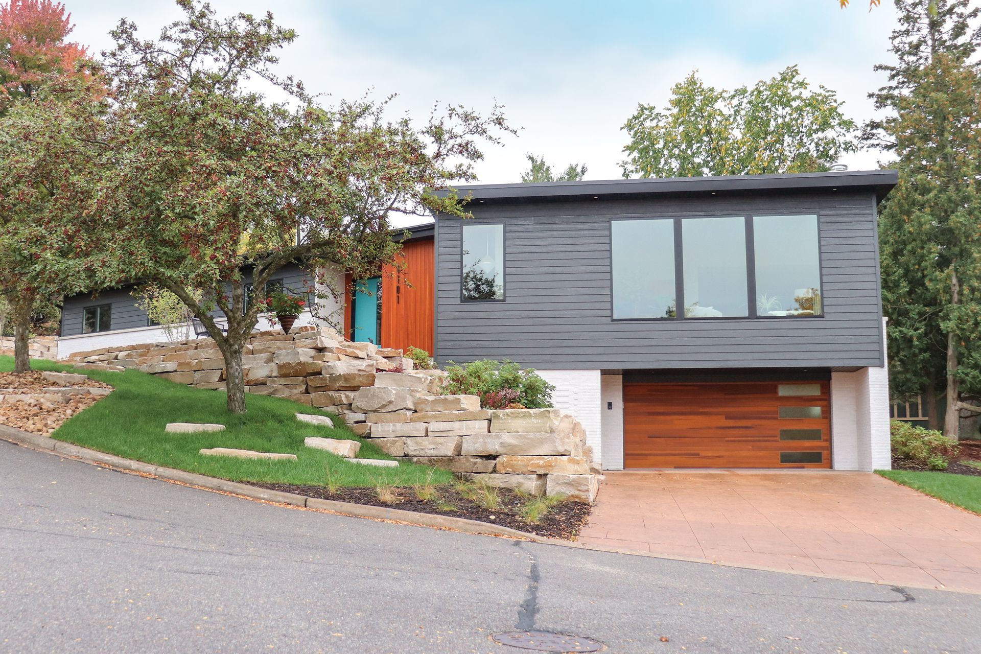 A house is sitting on top of a hill with trees in front of it.