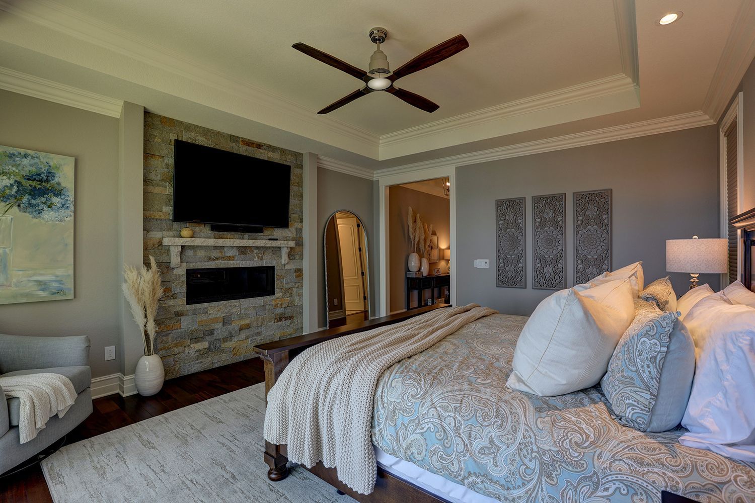 A bedroom with a bed , television , fireplace and ceiling fan.