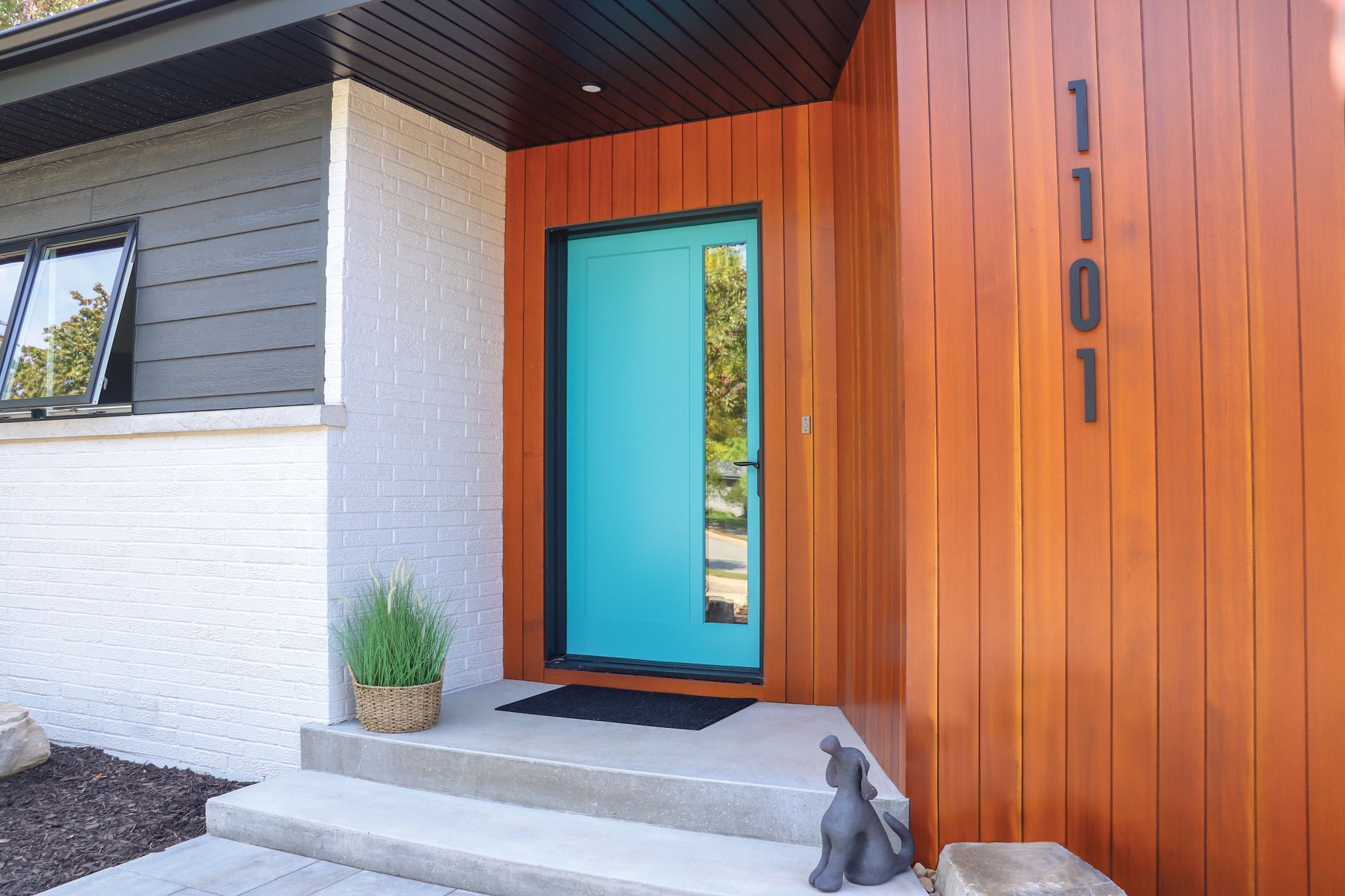The front door of a house with a blue door and the number 1101 on it.