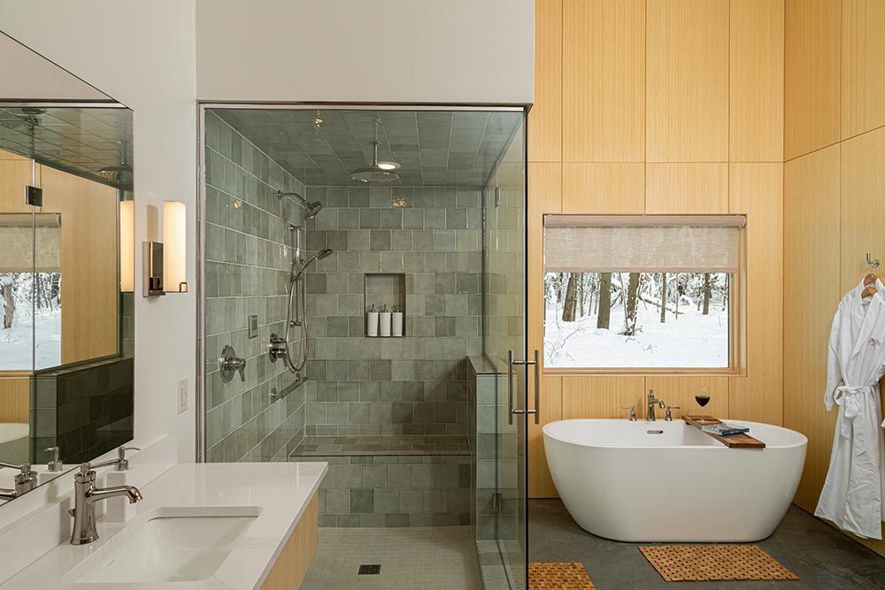 A bathroom with a tub , sink , shower and window.