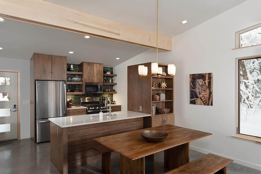 A kitchen and dining room in a house with a table and benches.