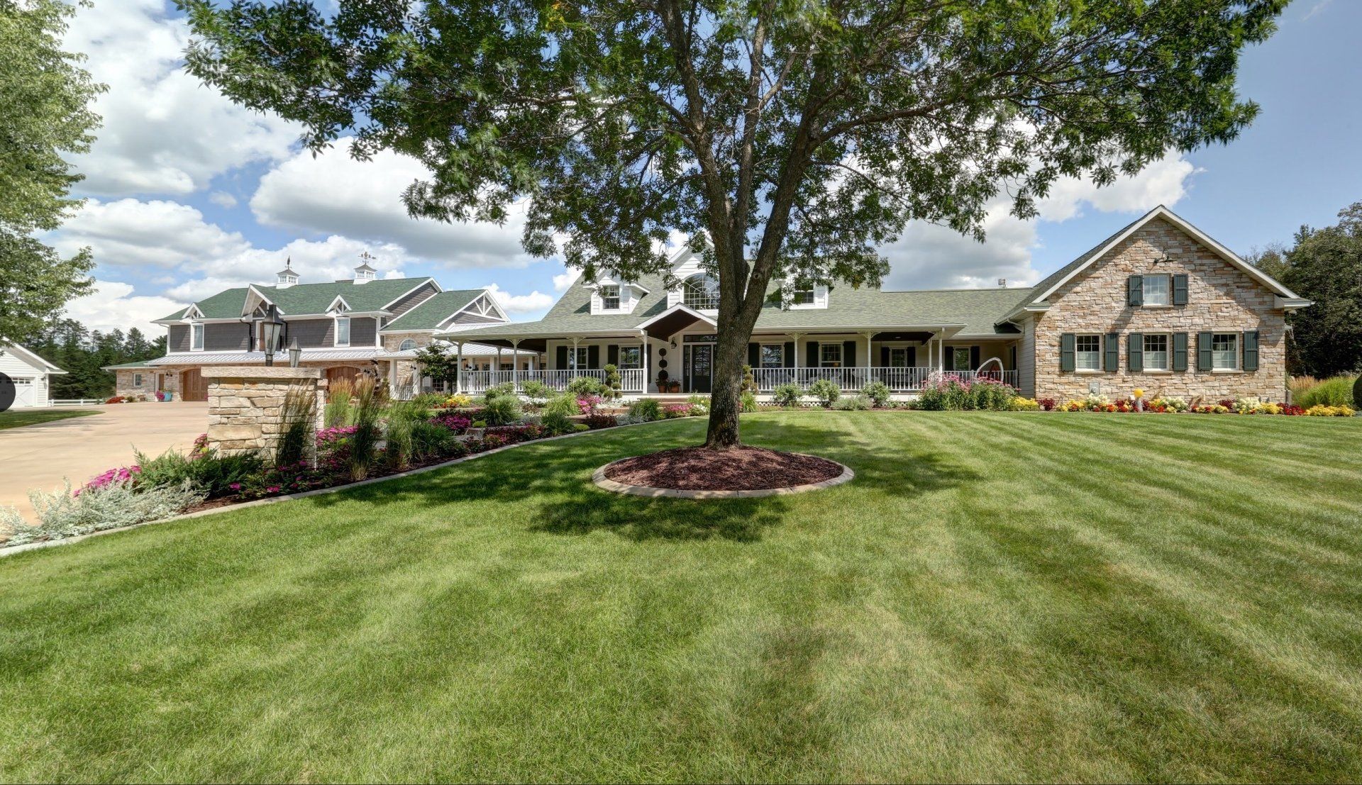 A large house with a lush green lawn and a tree in front of it