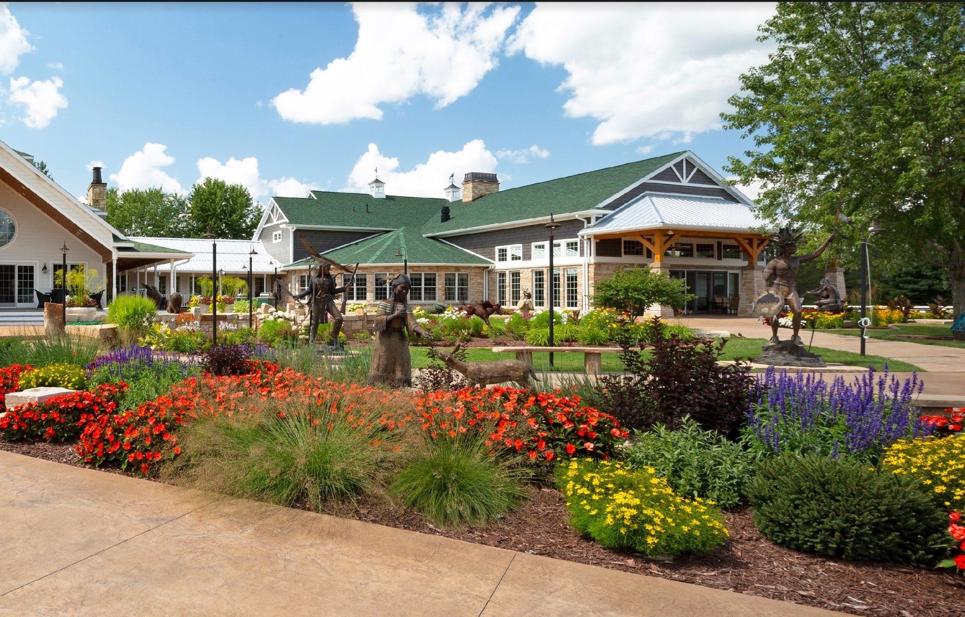 A large building with a green roof is surrounded by flowers