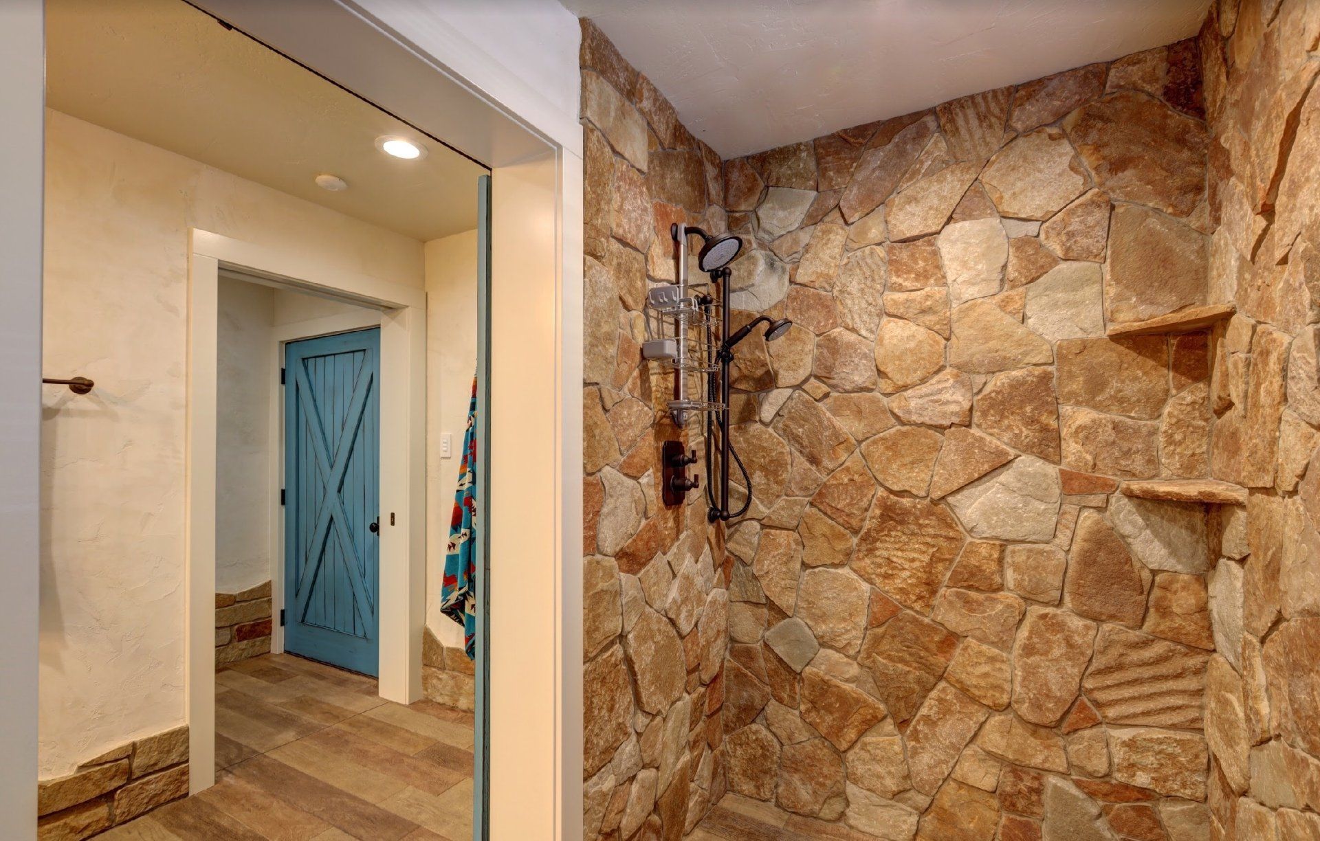 A bathroom with a walk in shower and a stone wall.