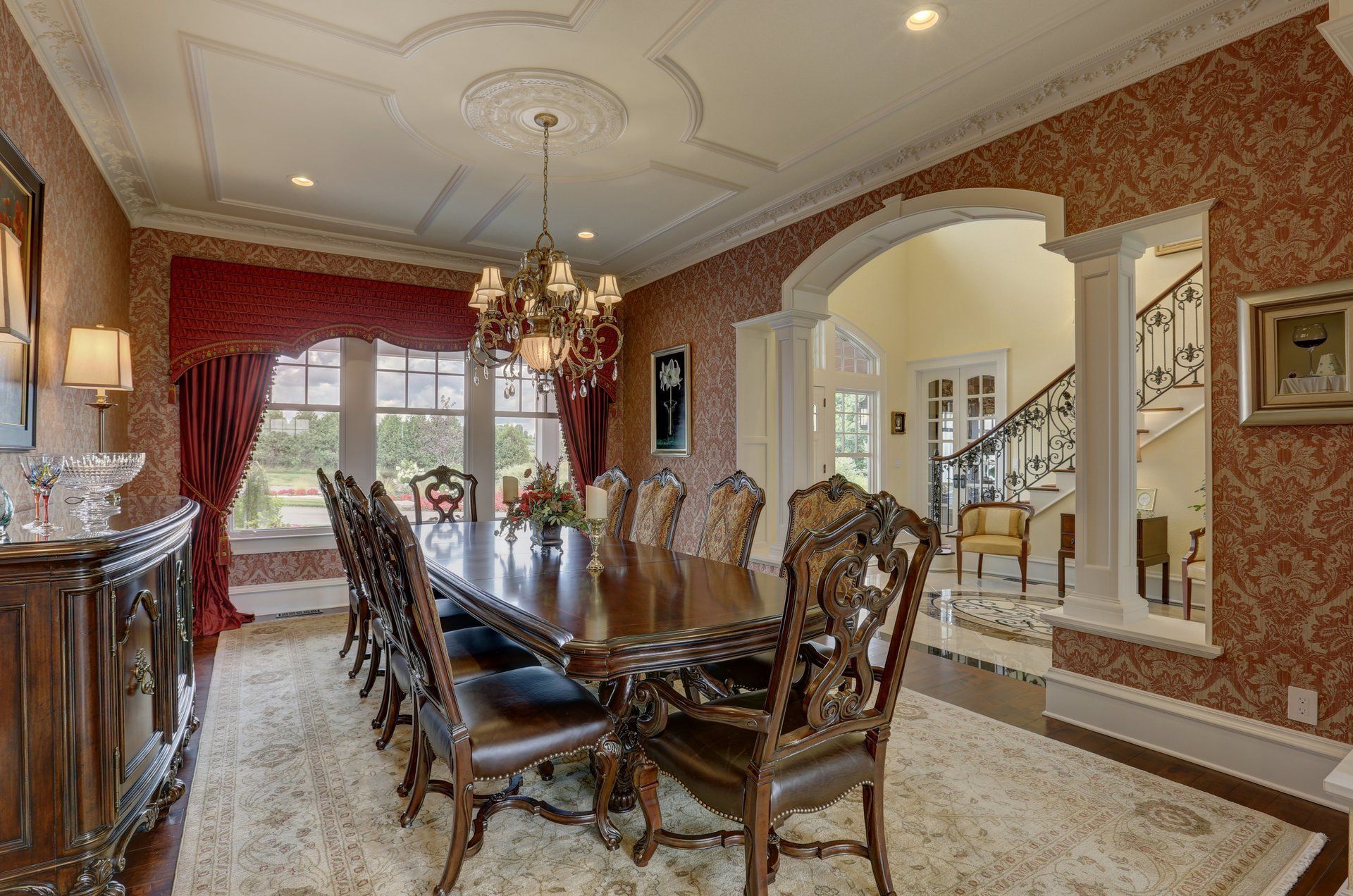 A dining room with a long table and chairs and a chandelier hanging from the ceiling.