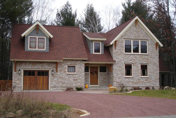 A large stone house with a red roof and a wooden garage door